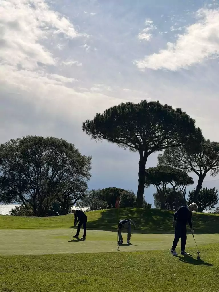 Golfergruppe auf dem Putting Green in Llavaneras mit mediterranen Pinien